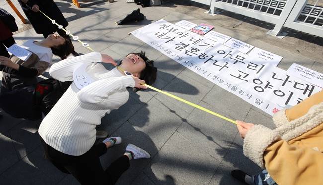 ⓒ연합뉴스 20대 여성들로 구성된 단체 '불꽃페미액션'이 27일 오전 정부서울청사 앞에서 한 국책 연구기관 센터장의 출산율 하락 대책 발언을 규탄하는 퍼포먼스로 '눈높이' 림보를 하고 있다. 원종욱 한국보건사회연구원 인구영향평가센터장은 최근 포럼에서 출산율 하락의 원인이 여성의 고학력과 사회진출이라며 불필요한 휴학·연수 여성에게 취업 불이익을 주자고 주장했다. 2017.2.27
