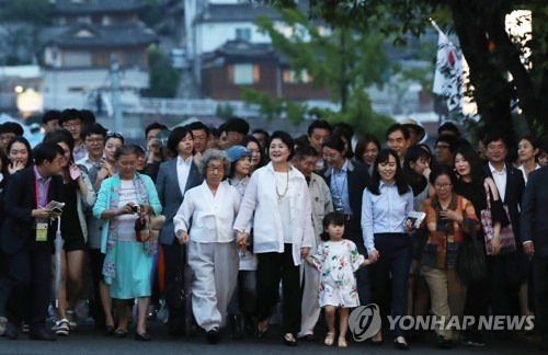 (서울=연합뉴스) 김주형 기자 = 문재인 대통령 부인 김정숙 여사(가운데)가 26일 오후 '열린 청와대 50년 만의 한밤 산책' 행사에 참석하기 위해 시민들과 함께 청와대 앞길을 걷고 있다. 2017.6.26      kjhpress@yna.co.kr