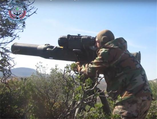 시리아 반군이 시리아 서부 구릉지역에서 나무 뒤에 숨어 토우 대전차 미사일을 조준하고 있다.