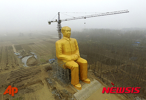 In this Monday, Jan. 4, 2016 photo, a 36.6-meter (120-foot) tall gold-colored statue of former Chinese leader Mao Zedong is surrounded by farmland in Tongxu County in central China's Henan province. According to Chinese state media, businessmen and local villagers contributed nearly 3 million yuan ($457,000) to build the cement statue. (Chinatopix via AP) CHINA OUT