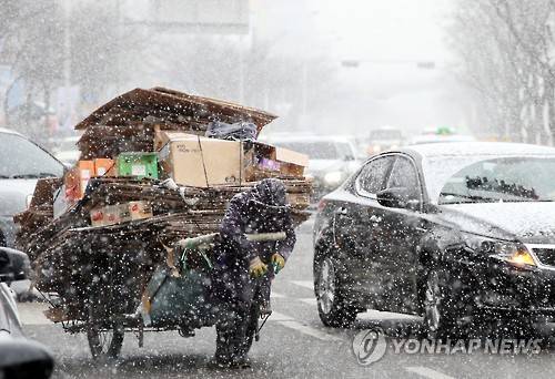 (광주=연합뉴스) 박철홍 기자 = 광주·전남에 내일까지 최고 30㎝의 폭설이 예보된 23일 오후 광주 서구 치평동의 한 도심 거리에서 한 노인이 길거리에서 거둬들인 폐지를 수레에 싣고 눈발을 헤치며 힘겨운 걸음을 내디디고 있다. 2016.1.23 pch80@yna.co.kr
