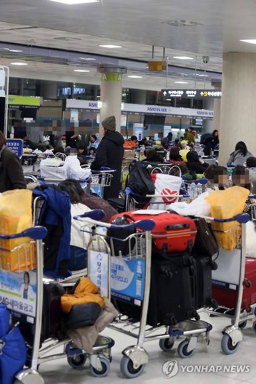 (제주=연합뉴스) 고성식 기자 = 24일 새벽 제주공항 내 항공사의 항공권 발권데스크 앞에서 항공편 운항이 재개되기를 바라는 많은 체류객이 쪽잠을 청하거나 이야기를 나누고 있다. 2016.1.24     koss@yna.co.kr