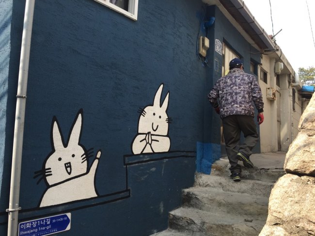 A resident walks into his home where the wall is painted with a mural in Ihwa-dong. (Kim Da-sol/The Korea Herald)