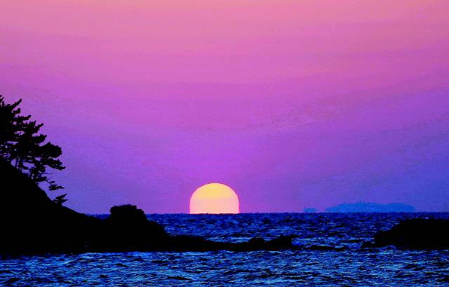 동백나무숲 입구 주차장 옆에서 바라본 오력도 해넘이. 사진 이병학 선임기자