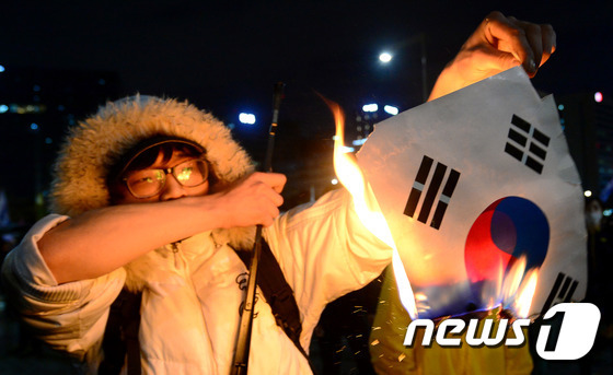 세월호 참사 1년 전국 집중 범국민대회 참가자가 지난해 4월 서울 광화문 앞에서 경찰과 대치하는 도중 태극기를 불태우고 있다. /뉴스1 © News1 박정호 기자