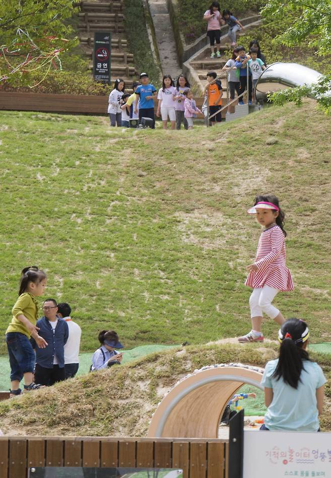 잔디 언덕 위쪽에 아이들이 길게 줄지어 서 있습니다. 언덕에 파묻힌 원통형 미끄럼틀을 타기 위해서입니다. 어두컴컴한 미끄럼을 타면 마치 동굴을 탐험하는 기분이라고 합니다. 사진 프리랜서 오종찬