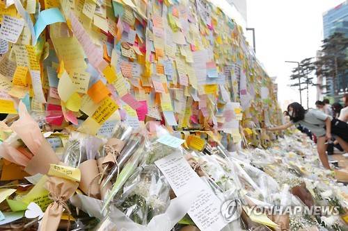 강남역 '묻지마 살인' 주말에도 계속되는 추모     (서울=연합뉴스) 진연수 기자 = 21일 오후 서울 강남역 '묻지마 살인사건' 피해자 여성을 추모하는 추모의 벽에 한 시민이 문구를 적은 메모지를 붙이고 있다. 2016.5.21     jin90@yna.co.kr