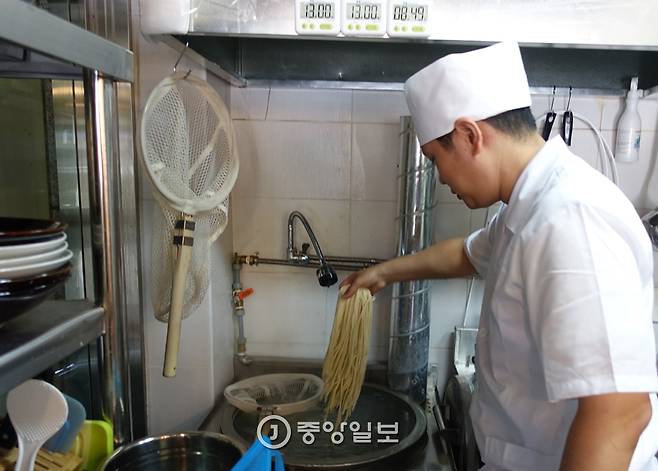 우동 삶는 가마에 자신이 뽑은 생면을 넣고 있는 박상현 셰프. 알람시계는 우동 삶는 시간 13분을 알려준다.