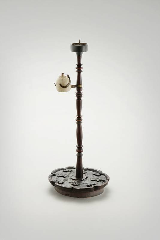 상단은 촛대, 기둥 중간에는 등잔받침이 있는 촛대겸용 목제등잔대. 연잎 형태의 밑받침에 `부귀다남(富貴多男)`을 양각했다.