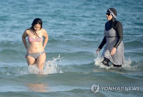 북아프리카 튀니지 해변에서 부르키니(오른쪽)와 비키니(왼쪽)를 입고 수영을 즐기는 여성들 [AFP=연합뉴스]