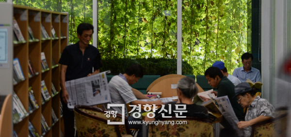 24일 ‘녹색커튼’이 드리워진 서울 노원구 구립정보도서관 연속간행물실에서 주민들이 신문을 읽고 있다. 이준헌 기자