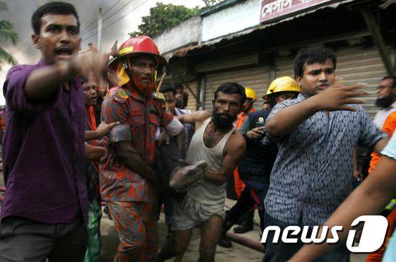방글라데시 구조 대원과 자원 봉사자들이 공장 화재 희생자 시신을 옮기고 있다. © AFP=뉴스1