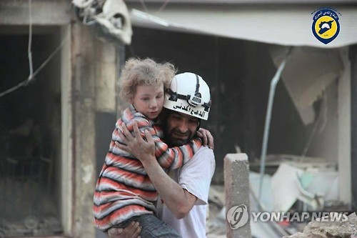 2016년 시리아 알레포에서 하얀헬멧 대원이 구조한 어린이를 안고 나오는 모습 [EPA/SYRIA CIVIL DEFENCE=연합뉴스 자료사진]