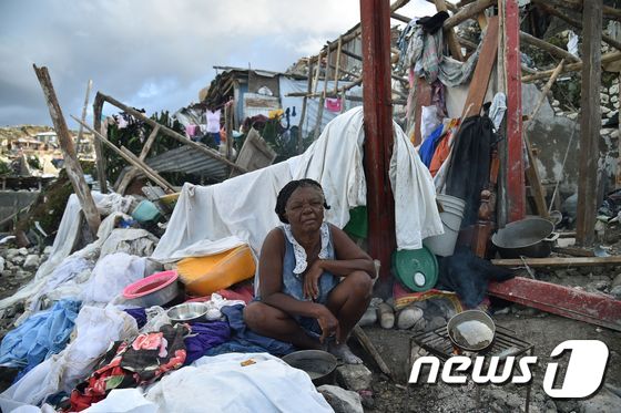 한 아이티 여성이 7일(현지시간) 살인 허리케인 '매튜'가 휩쓸고 지나간 자신의 집 잔해 위에 앉아 있다. © AFP=뉴스1