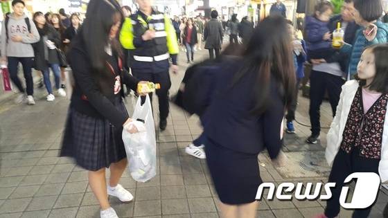 12일 부산 서면에서 열린 시국집회에 참여한 여고생들이 자발적으로 쓰레기를 줍고 있다.© News1