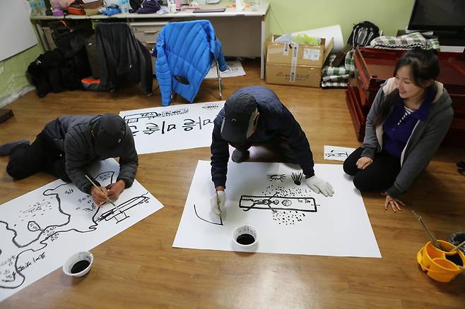 장도 부수마을 박복수(가운데) 이장과 박보수(왼쪽) 어촌계장이 마을회관에서 장도 소개 그림을 그리고 있다.
