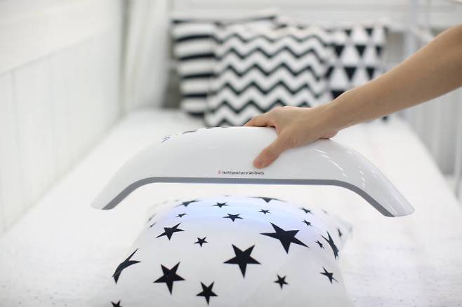 프라임테크의 살균기 `브이레이`로 침구를 살균하는 모습