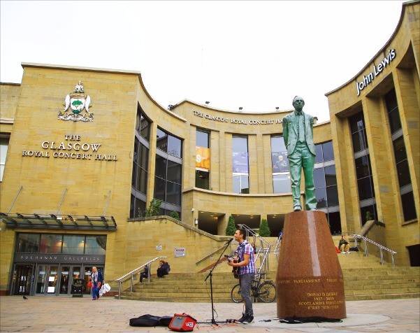 로열 앨버트홀 앞에서 기타를 치며 노래하는 버스커.