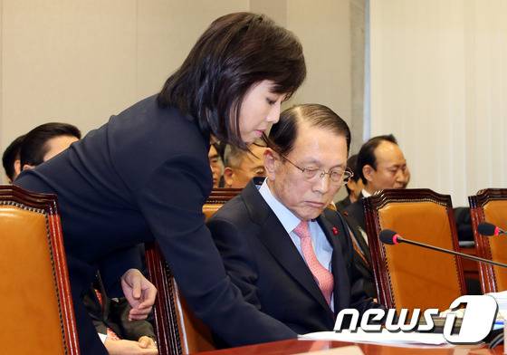 청와대 문건유출 관련 현안보고를 위해 9일 오전 서울 여의도 국회에서 열린 운영위원회 전체회의에 출석한 조윤선 청와대 정무수석이 김기춘 대통령비서실장에게 탁자 밑으로 조심스럽게 물잔을 건네고 있다.2015.1.9/뉴스1 © News1 이광호 기자