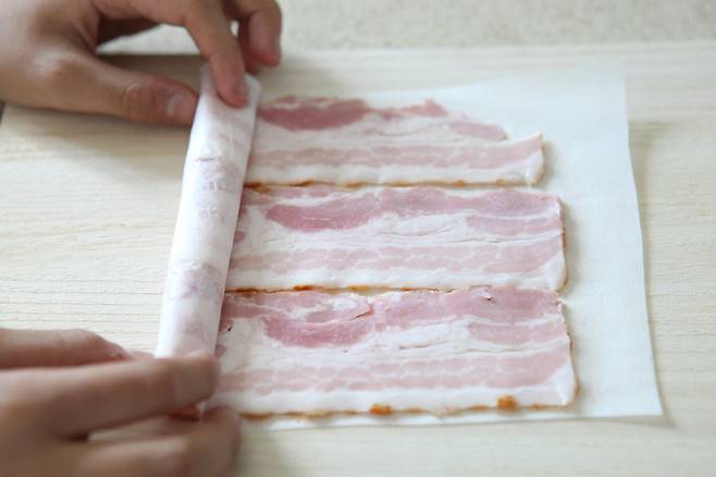 종이포일 위에 삼겹살이나 베이컨을 한 장씩 올려놓고 한쪽 끝부터 돌돌 만다.