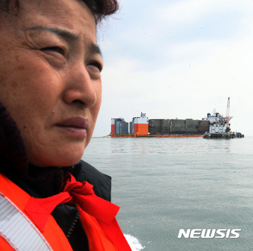 【진도=뉴시스】신대희 기자 = 26일 오전 전남 진도군 맹골수도에서 중국 인양업체 상하이샐비지가 반잠수식 선박에 부양된 세월호 선체의 배수 작업을 벌이고 있다. 미수습자 단원고 양승진 교사의 아내 양백형씨가 세월호를 바라보고 있다. 세월호는 25일 오후 9시15분께 선체 전체가 해수면 위로 올랐다. 2017.03.26.    sdhdream@newsis.com