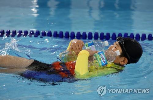 (제주=연합뉴스) 전지혜 기자 = 26일 제주시 삼성초등학교 수영장에서 외도초등학교 학생들을 대상으로 생존수영 교육이 진행된 가운데 한 어린이가 페트병의 부력을 이용해 물에 떠 보고 있다. 2017.4.26      atoz@yna.co.kr