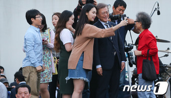 문재인 더불어민주당 대통령 후보가 사전투표 25% 프리허그 공약을 실행하기 위해 6일 서울 홍대 걷고싶은거리에서 열린 투표참여 릴레이 버스킹 vote0509에 참석해 시민들과 포옹한 뒤 기념촬영을 하고 있다. 2017.5.6/뉴스1 © News1 허경 기자