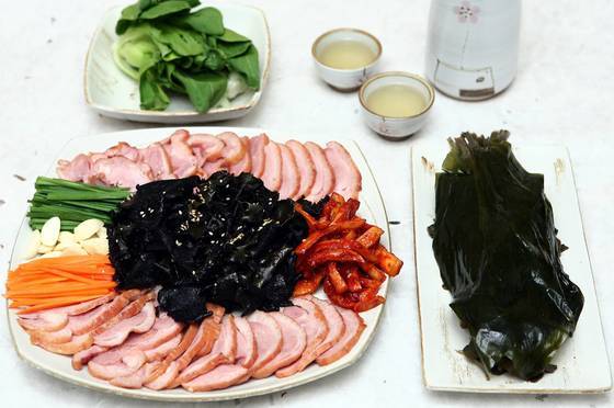 훈제오리고기에 석이버섯·무말랭이무침·부추를 올려 쌈채나 명이장아찌에 싸서 먹는 석이오리훈제보쌈. [사진 석이원]