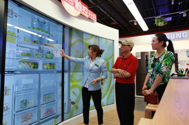 A Samsung Electronics employee introduces customers to home electronics products displayed at the Samsung Open House, an experience store that opened in Beijing last month. The tech giant will open the shop in global markets including the U.S. and some European nations this year. (Samsung Electronics)