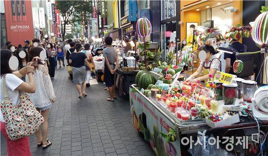 11일 저녁 서울 명동 거리. 외국인 관광객들이 생과일주스 노점을 사진에 담고 있다.(사진=오종탁 기자)