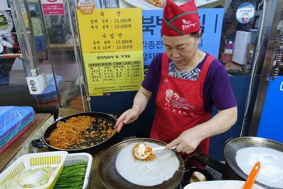 ‘신선칼국수’ 이웃에 있는 ‘북방부침’의 여주인이 얇게 부친 메밀부침에 소를 넣어 총떡을 만들고 있다.