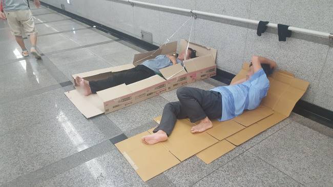 [사진=서울 중구 지하철 1ㆍ4호선 서울역 6ㆍ7번 출구 통로에서 두 노숙인이 종이박스를 깔고 누워있다. ]