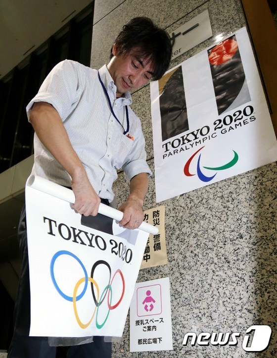 도쿄도청 직원이 지난 1일 밤 2020년 도쿄올림픽 엠블럼이 들어간 포스터를 떼내고 있다. © =News1
