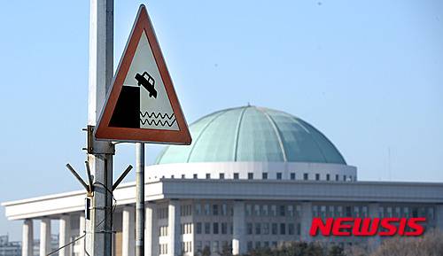 【서울=뉴시스】이종철 기자 = 12일 오전 서울 서강대교에 있는 한강 자동차추락 주의 도로 표지판이 뒤로 보이는 국회와 맞물려 추락하는 19대 국회를 상징하는 모습처럼 보이고 있다. 2016.01.12 jc4321@newsis.com