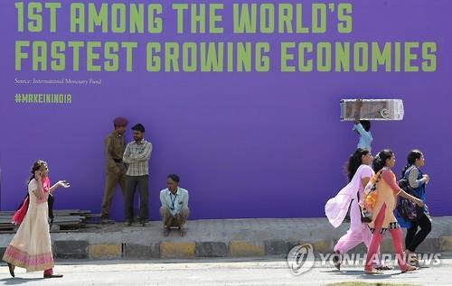 11일 인도 뭄바이에서 시민들이 인도의 빠른 경제성장을 알리는 글귀 아래를 지나가고 있다.(AFP=연합뉴스 자료사진)