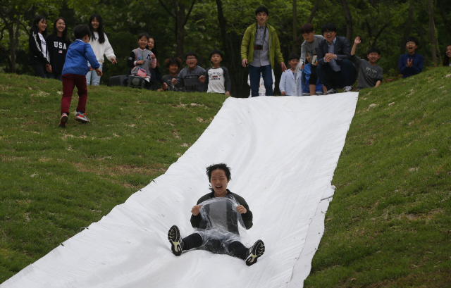잔디 미끄럼틀 타고… 비닐을 몸에 두른 어린이가 비탈진 언덕에 만들어진 ‘잔디 미끄럼틀’ 위로 썰매 타듯 질주하고 있다.순천/신소영 기자 viator@hani.co.kr