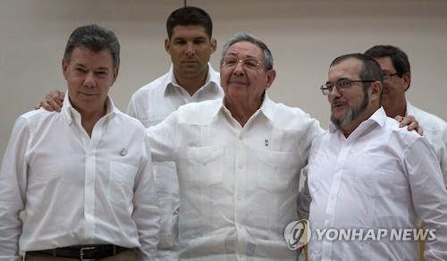 작년 9월 23일 쿠바 수도 아바나에서 후안 마누엘 산토스 콜롬비아 대통령(왼쪽)과 최대 반군 콜롬비아무장혁명군(FARC) 지도자 로드리고 론도뇨가 올해 3월까지 평화협정을 체결하기로 합의한 뒤 어깨동무를 하고 있다. 가운데 인물은 쿠바의 라울 카스트로 국가평의회 의장. [AP=연합뉴스 자료사진]
