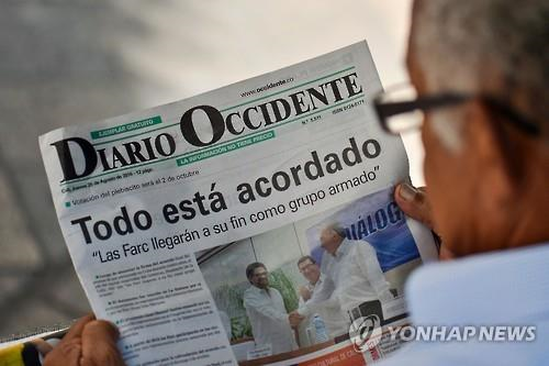 한 콜롬비아 시민이 25일(현지시간) 정부와 반군 FARC가 전날 체결한 평화협정에 대한 신문 머리기사를 읽고 있다. [AFP=연합뉴스]