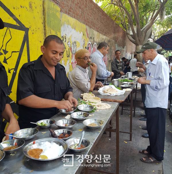 출근길 남성들이 타흐리르 광장 근처 골목길에서 풀 메다메스로 아침을 먹고 있다.