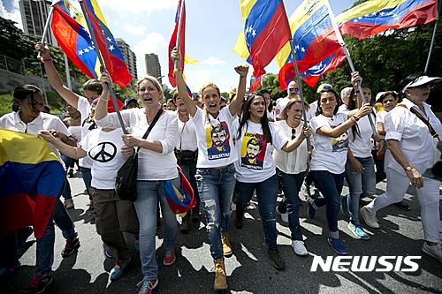 【카라카스(베네수엘라)=AP/뉴시스】 = 투옥된 베네수엘라 야당지도자 레오폴도 로페스의 부인 릴리언 틴토리(가운데)를 비롯한 구속인사 부인들이 22일(현지시간) 수도 카라카스에서 대통령소환 주민투표의 연기에 거세게 항의하며 시위대의 선두에서서 행진하고 있다.  야당은 선거 연기와 주민 서명운동 금지를 '쿠데타'로 규정하고 결전을 선언했다.