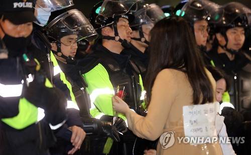 경찰은 죄없다 (서울=연합뉴스) 한상균 기자 = 19일 밤 청와대 진입로인 종로구 내자동 로터리에서 박근혜 대통령 퇴진촉구 촛불집회에 참가한 한 여성이 시위대를 막고 있는 경찰에게 장미꽃을 건네고 있다.