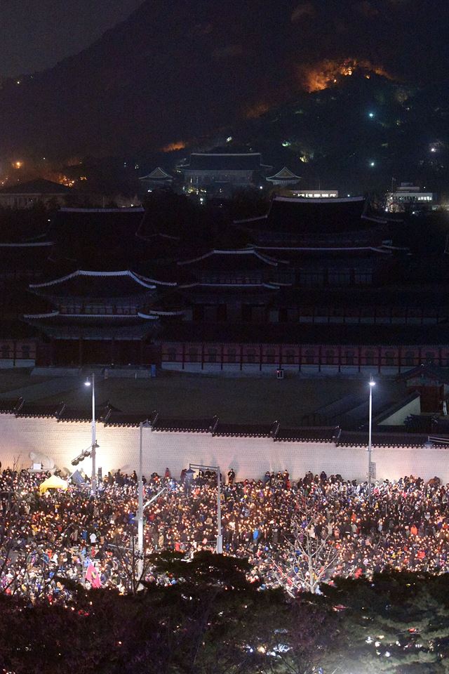 3일 밤 서울 광화문광장에서 청와대 방향으로 이동하는 촛불 행렬 뒤로 암흑과 정적에 휩싸인 청와대가 보이고 있다. 사진공동취재단