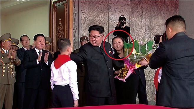 2016년 5월10일 주석단에서 김정은의 꽃다발을 직접 챙겨주는 김여정(붉은 원) © 조선중앙통신 연합