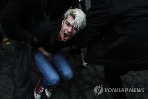 20일 워싱턴에서 反트럼프 시위 도중 한 참가자가 경찰이 쏜 콩주머니탄환에 맞아 고통스러워하고 있는 모습 [AP=연합뉴스]