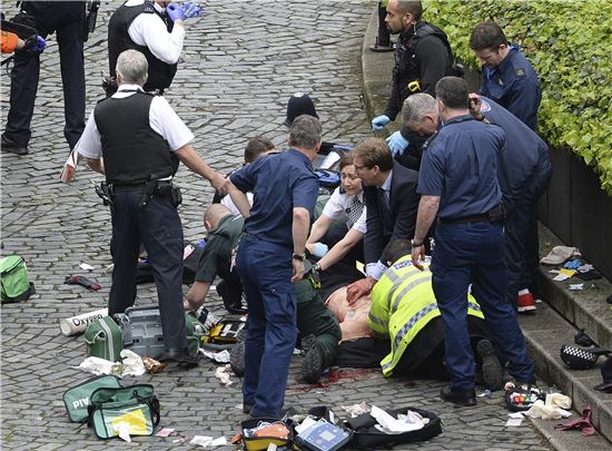 엘우드 영국 외무차관(가운데)이 런던 테러로 부상당한 경찰관을 응급처치하고 있다. (사진=AP연합)