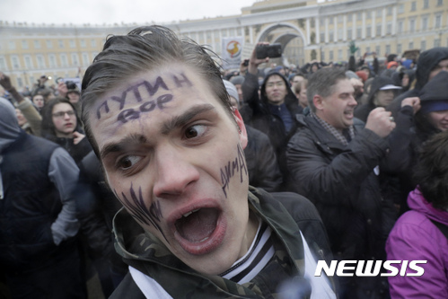 【 상트페테르부르크=AP/뉴시스】러시아 상트페테르부르크에서 26일(현지시간) 대규모 반부패, 반정부 시위가 벌어지고 있다. 남성의 얼굴에 씌여있는 문구는 러시아어로 "푸틴은 도둑"이란 의미이다. 2017.03.27