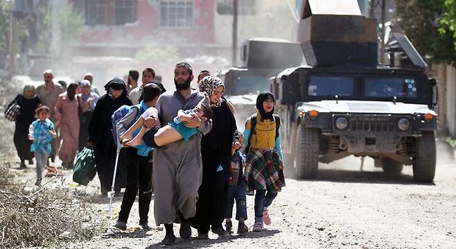 17일(현지 시각) 이라크군과 이슬람국가(IS) 대원들이 전투를 벌인 이라크 모술 서부 지역에서 주민들이 피란길에 오르고 있다. 야히야 라술 이라크군 대변인은 전날 기자회견에서 “IS의 최대 근거지 모술 서부를 90% 정도 탈환했다”고 밝혔다. /AFP 연합뉴스
