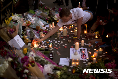 【맨체스터(영국) = AP/뉴시스】23일(현지시간) 영국 맨체스터 시내의 앨버트 광장에 마련된 테러 희생자 추모의 장소에서 한 남성이 촛불을 켜고 있다. 2017.05.24