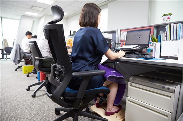 아모레퍼시픽 직원이 사무실에서 임신부가 편안히 근무할 수 있도록 돕는 전용 의자와 다리 붓기 방지용 발 받침대, 전자파 차단 담요 등 ‘예비맘 배려 3종 세트’를 사용하고 있다.아모레퍼시픽 제공