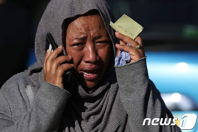 런던 화재 현장에서 사라진 친척을 찾으려고 전화하다가 울음을 터뜨리는 시민. © AFP=뉴스1